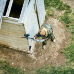 person in green and brown camouflage jacket and pants playing paintball